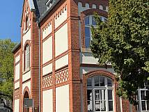 Außenansicht eines historischen Backsteingebäudes mit dekorativen Fassadenelementen und großen Fenstern