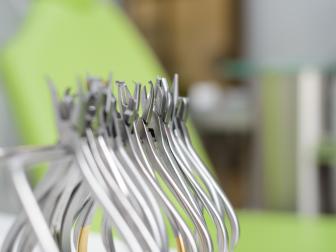 Nahaufnahme von mehreren sterilen kieferorthopädischen oder zahnmedizinischen Zangen auf einem Tablett in einer Praxis, im Hintergrund ein grüner Behandlungsstuhl.